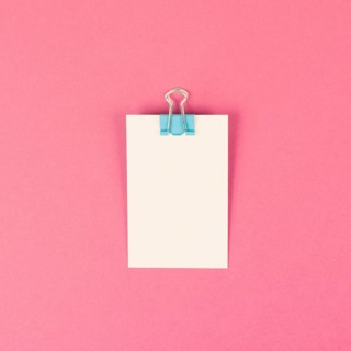 Blank white paper with a paperclip on a pink colored background, copy space for text, reminder or