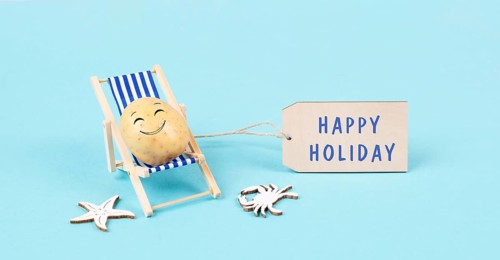 Potato with a funny face is sitting in lounge chairs, sign with the words happy holiday, greeting