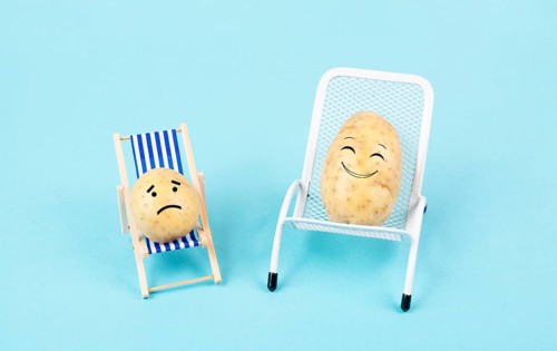 Potatoes with funny faces sitting in lounge chairs and having a conversation, the small one is sad,