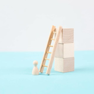 Man is standing next to a ladder, climbing up in career, having a goal, brainstorming for ideas,