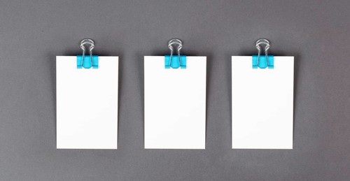 Blank white papers with a paperclip on a gray colored background, copy space for text, reminder or