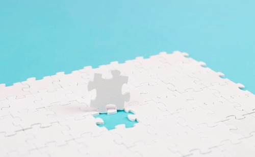 White jigsaw on a blue background, missing parts, working together as a team, searching for
