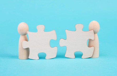 Two men with puzzle pieces built a team, connect the parts together, corporate in teamwork,