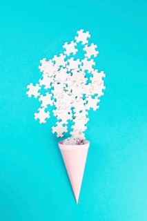 Cone with white puzzle pieces, blue background, spreading the jigsaw parts, searching for ideas and