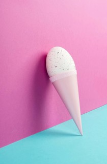 Ice cream cone with an egg, pink and blue background, copy space, easter holiday, summer season,