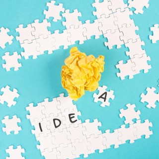 Puzzle on a blue background, yellow crumbled paper, word idea is standing on the jigsaw pieces,