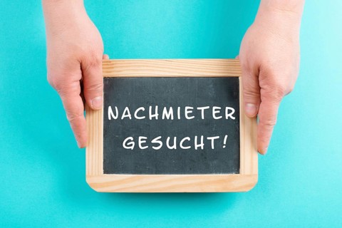 Holding a chalkboard in the hands, looking for a new tenant is standing in german language on the