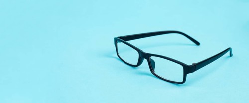 Glasses with a black frame on a blue background, copy space for text