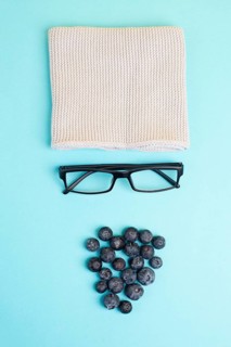 Human face made with a wool hat, glasses and blueberries as a beard, funny minimalist portrait, eco