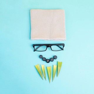Human face of a man made with a wool hat, glasses and leaves as a beard, funny minimalist portrait,