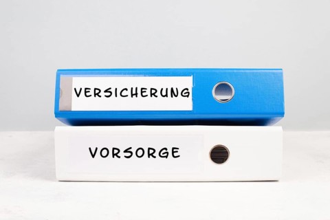 Two folders with the words insurance and precaution in german langauge, documents at an office,