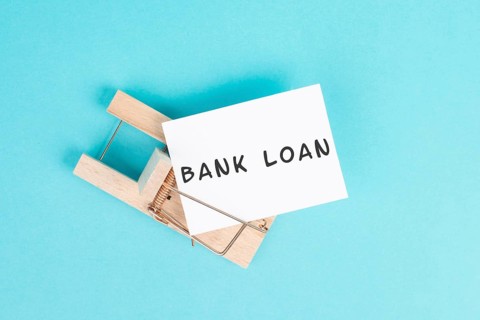 Paper with the words bank loan in a mousetrap, finanicial debt, inflation, risky credit and