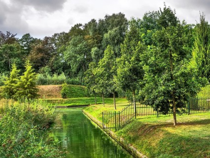 Green parkland with canal, fenced by trees, reflecting water and green meadow, groenlo, gelderland,