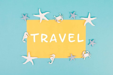 The word travel is standing on a yellow colored paper, sea stars, seahorses and crab bulding a