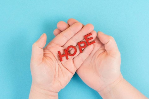 Holding the word hope in the palm of the hands, trust and believe concept, having faith in the