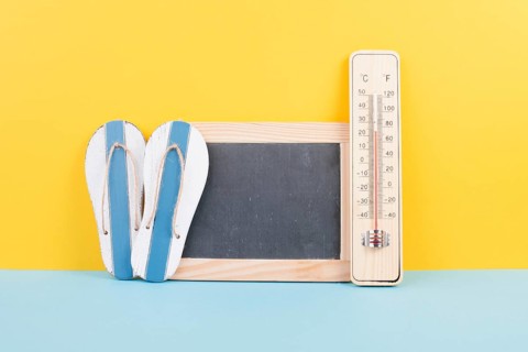 Empty chalkboard with a thermometer and flip flops, holiday background, summer vacation, hot