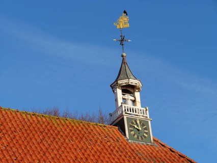 Church tower with clock and golden weather vane under a clear sky, greetsiel, east frisia, germany