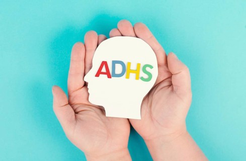 Hands holding a head with the german word ADHS which means attention deficit hyperactivity