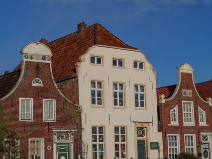 Three historic houses with ornate facades and gables under a clear sky, greetsiel, east frisia,