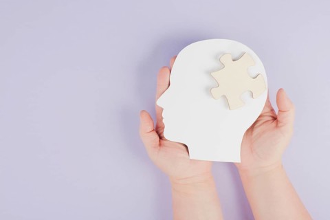Holding a head with a puzzle piece, mental disease like Autism, Alzheimer, stroke awareness,