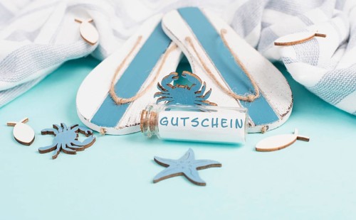 Blue colored summer and vacation background, flip flops, sea stars and a glass bootle with the word