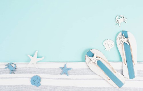 Blue colored summer and holiday background, flip flops, sea stars and fish with copy space, travel