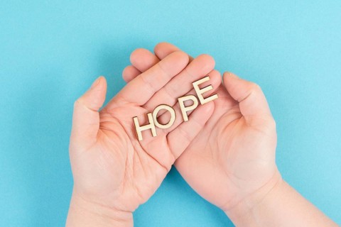 Holding the word hope in the palm of the hands, trust and believe concept, having faith in the