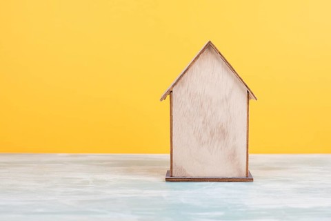 Wooden house, yellow background, buying or renting a house, real estate concept, booking home for