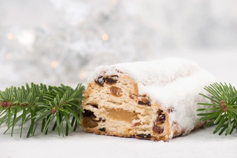 Christstollen, traditonal christmas cake with nuts, raisons, marzipan on a blue background, empty
