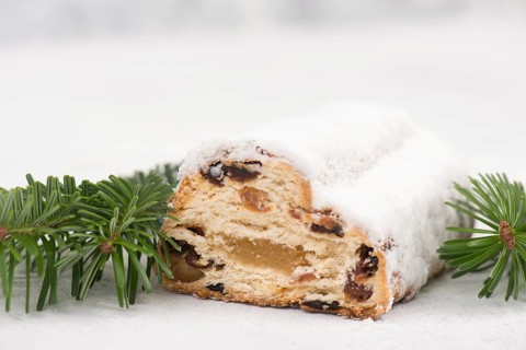 Christstollen, traditonal christmas cake with nuts, raisons, marzipan on a blue background, empty
