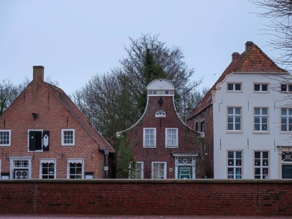 Three historic house fronts with brick facades in front of a cloudy sky, greetsiel, east frisia,