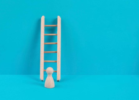 Man is standing next to a ladder, climbing up in career, having a goal, brainstorming for ideas,