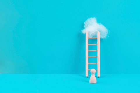 Man is standing next to a ladder, climbing up in career, having a goal, brainstorming for ideas,