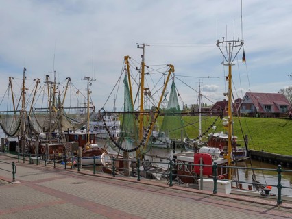 Several fishing boats with stretched nets in the quiet harbour at the pier under a cloudy sky,