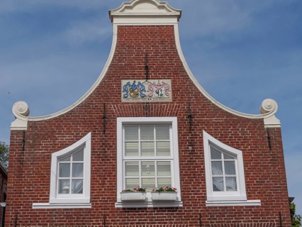 A facade of a historic building with red brick walls and white window frames, Greetsiel, East