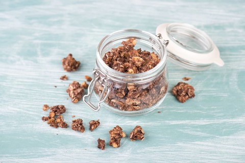 Muesli with chocolate in a glass on a turquoise blue and white shabby background, empty space for