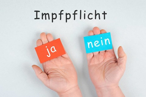 Mandatory vaccination, german language, yes and no is standing on paper, making a decision,