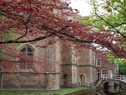 Scene of an old brick building with a red tree, a small bridge and a quiet canal, Delft, Holland,