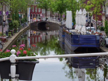 Scenic canal view with blooming flowers, a small bridge and a quiet city atmosphere, Delft,