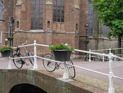 Canal bridge with bicycles and flower pots next to historic brick buildings, Delft, Holland,