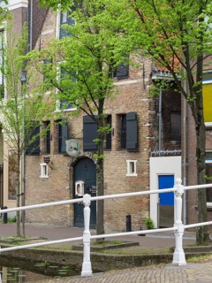Old brick house with shutters and trees on the canal, Delft, Holland, Netherlands