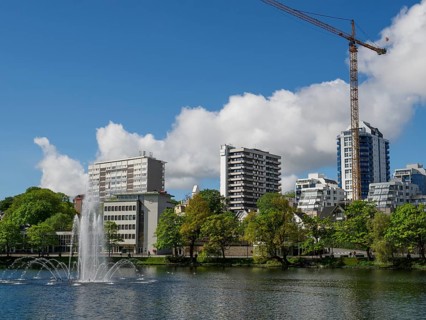 City skyline with a lake and fountain, surrounded by modern buildings and a crane, Stavanger,