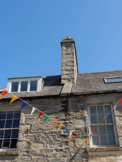 Stone building with colourful flags and a chimney under a clear sky, lerwick, shetlands, scotland,
