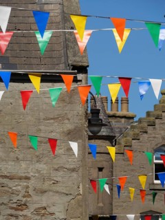 Colourful flags hang between traditional buildings under a bright sky, lerwick, shetlands,