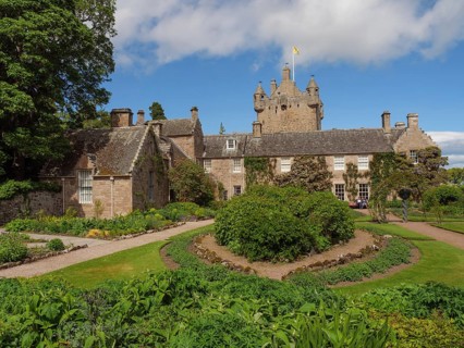 Historic castle with towers and surrounding garden, lush vegetation and a sunny sky, inverness,