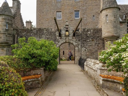 A historic entrance with Tor tor to a castle, flanked by stone walls and benches, inverness,