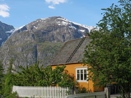 Cosy house with white fence and trees in a green village surrounded by high mountains, Eidfjörd,