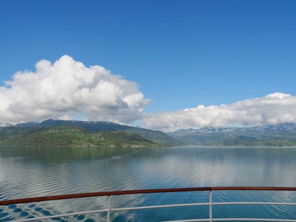 Pristine lake with calm water and mountains in the background, clear blue sky and clouds, Eidfjörd,