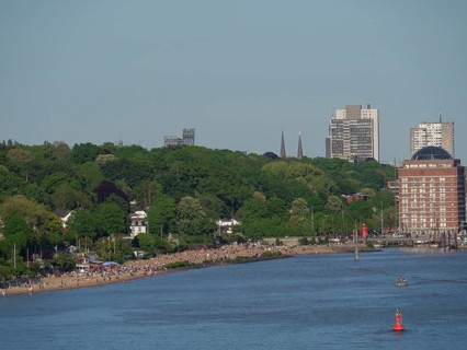 Shoreline landscape with a long beach and many people, surrounded by green nature, Elbe, Hamburg,
