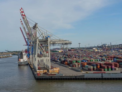 Large cranes in the harbour loading containers, cargo ship at the quay, many containers stacked,